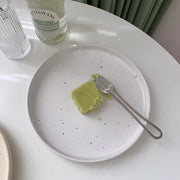 Three minimalist speckled ceramic plates in cream, light grey, and sage green