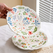 Colorful floral ceramic plates stacked on a table, showcasing intricate and vibrant flower and leaf patterns
