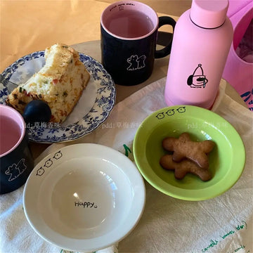 Set of happy ceramic bowls and cups with cheerful designs and vibrant colors