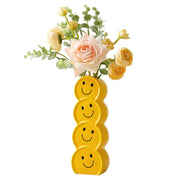 Bright yellow ceramic vase with a hand-painted smiley face