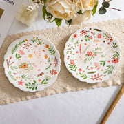 Colorful floral ceramic plates stacked on a table, showcasing intricate and vibrant flower and leaf patterns
