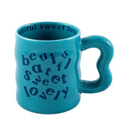 Blue aesthetic wavy ceramic mugs with quirky "beautiful, sweet, lovely" text, against a neutral background.