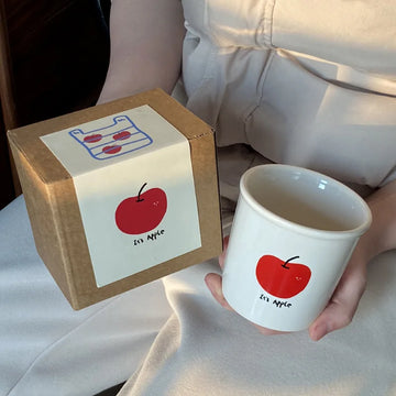 Adorable ceramic mug with playful cartoon design an apple with "No Banana No Tomato" text.
